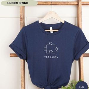 This navy t-shirt has a white image of a puzzle piece centred in the middle, with the word therapy underneath. Tailored towards people who enjoy puzzles also who find puzzles a form of therapy.