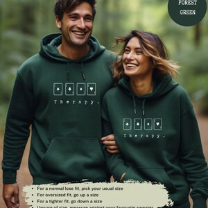 This forest green hoodie has a white image of playing cards centred in the middle, with the word therapy underneath. Tailored towards people and couples who enjoy playing cards games also who find playing card games a form of therapy.