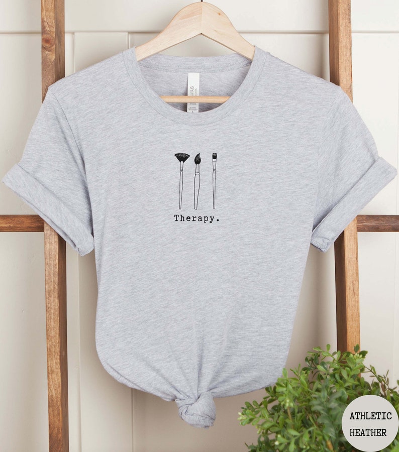 This athletic heather t-shirt has a black image of three paintbrushes centred in the middle, with the word therapy underneath. Tailored towards people who enjoy painting also who find painting a form of therapy.