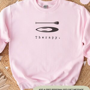 This pink sweatshirt has a black image of a sup board centred in the middle, with the word therapy underneath. Tailored towards people and couples who enjoy sup boarding also who find sup boarding a form of therapy.