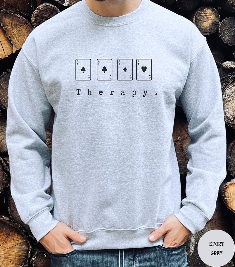 This sport grey sweatshirt has a black image of a playing cards centred in the middle, with the word therapy underneath. Tailored towards people who enjoy playing cards also who find card games a form of therapy