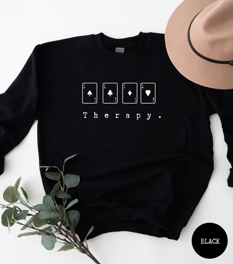 This black sweatshirt has a white image of a playing cards centred in the middle, with the word therapy underneath. Tailored towards people who enjoy playing cards also who find card games a form of therapy