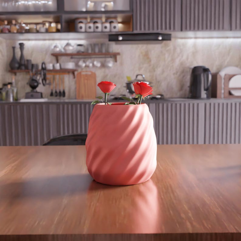 May include: A pink ceramic vase with a swirl design, holding two red roses.