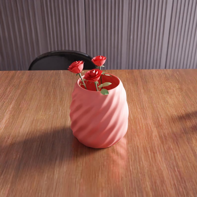 May include: A pink ceramic vase with a swirl design, holding three red paper roses.
