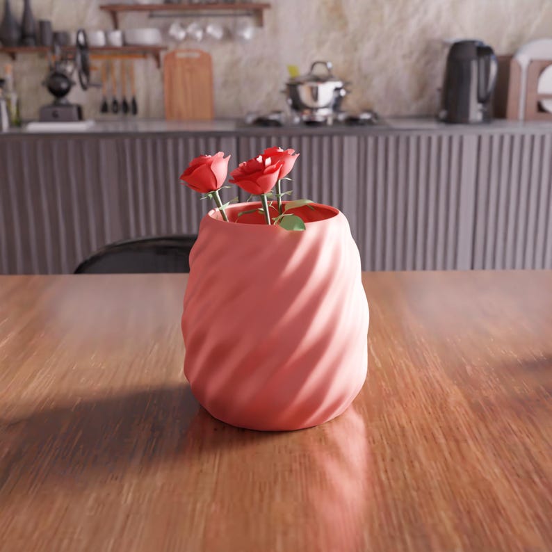 May include: A pink ceramic vase with a swirl design, holding three red roses.