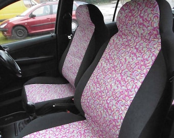 Puede incluir: Dos fundas para asientos de coche con un patrón de espiral rosa y blanco. Las fundas son negras en la parte posterior y los lados. Los asientos delanteros están en el interior de un coche.