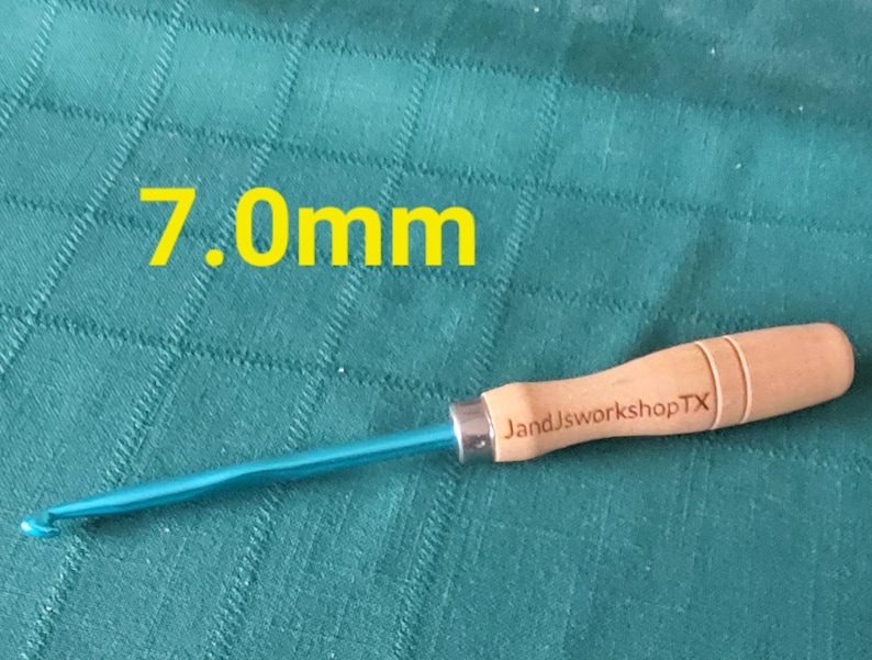 May include: A 7.0mm crochet hook with a blue metal hook and a wooden handle. The handle is engraved with "JandJworkshopTX".