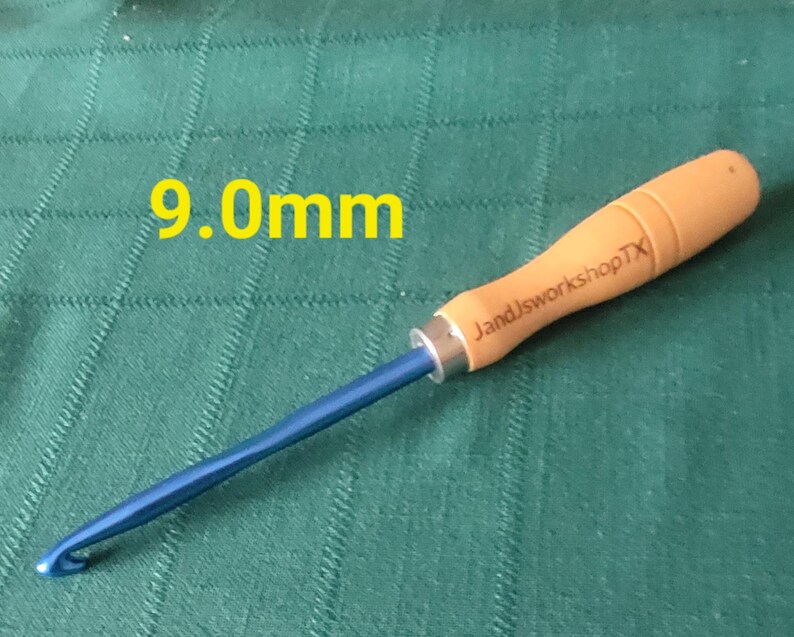 May include: A 9.0 mm crochet hook with a blue metal hook and a wooden handle. The handle is engraved with "JandJworkshopTX".