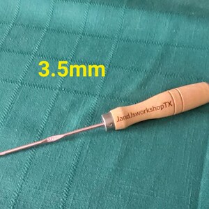 May include: A 3.5 mm crochet hook with a wooden handle. The handle is engraved with "JandJworkshopTX".