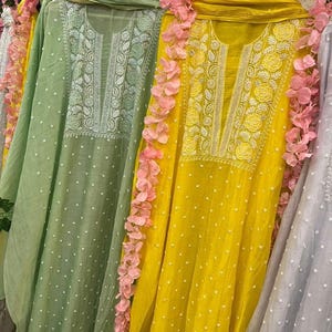 May include: Three long, flowing, embroidered dresses in green, yellow, and grey with white polka dots. The dresses have a white embroidered neckline and are displayed on hangers.