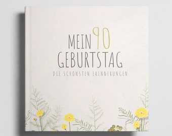 May include: A white book cover with the text "Mein 90 Geburtstag Die schönsten Erinnerungen" in black and yellow. The cover is decorated with a border of yellow flowers and green leaves.