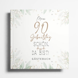 Peut inclure: Un livre d'or blanc avec un motif floral vert et or. Le texte sur la couverture est "Mein 90 Geburtstag Schön. dass du da bist! Gästebuch".