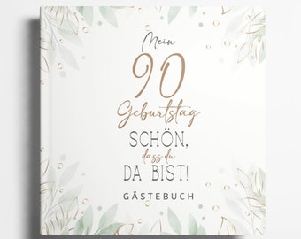 May include: A white guest book with a green and gold floral design. The text on the cover reads "Mein 90 Geburtstag Schön. dass du da bist! Gästebuch".
