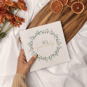 May include: A white card with a green leafy wreath design and the text "30. Geburtstag" in gold lettering.