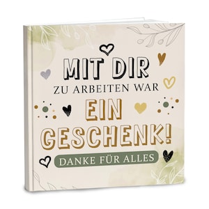 Può includere: Un libro quadrato con copertina rigida color crema che riporta il testo in tedesco MIT DIR ZU ARBEITEN WAR EIN GESCHENK! DANKE FÜR ALLES. Il design include cuori neri e dorati disegnati a mano, piccoli punti e delicate illustrazioni botaniche.