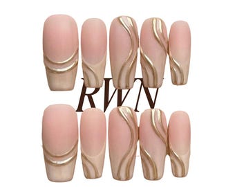 May include: A set of ten press-on nails in a soft nude pink base colour, featuring metallic gold swirl and line accents. The nails are arranged in two rows of five, with the text RWN centred between them and Rich Wife's Nails by Pinneacle below.