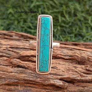 May include: A silver ring with a turquoise stone set in a rectangular shape.