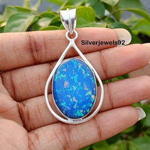 May include: A silver pendant with a teardrop-shaped design featuring a blue opal stone with iridescent flecks. The pendant is set in a silver frame and has a bail for attaching to a chain.