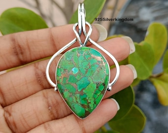 May include: A teardrop-shaped green turquoise pendant with copper inclusions set in a sterling silver bail. The pendant is approximately 2 inches long and 1 inch wide. 925Silverkingdom.