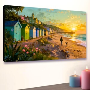 Puede incluir: Una impresión en lienzo que representa una escena de playa al atardecer. Cabañas de playa coloridas bordean la costa, con una persona paseando a un perro por la arena. El sol se pone sobre el océano, creando una luz cálida. Un muelle se extiende hacia el agua.