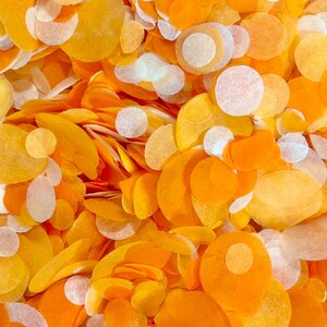 May include: A close-up of a pile of orange and white confetti. The confetti is made of paper and is in various shapes and sizes.