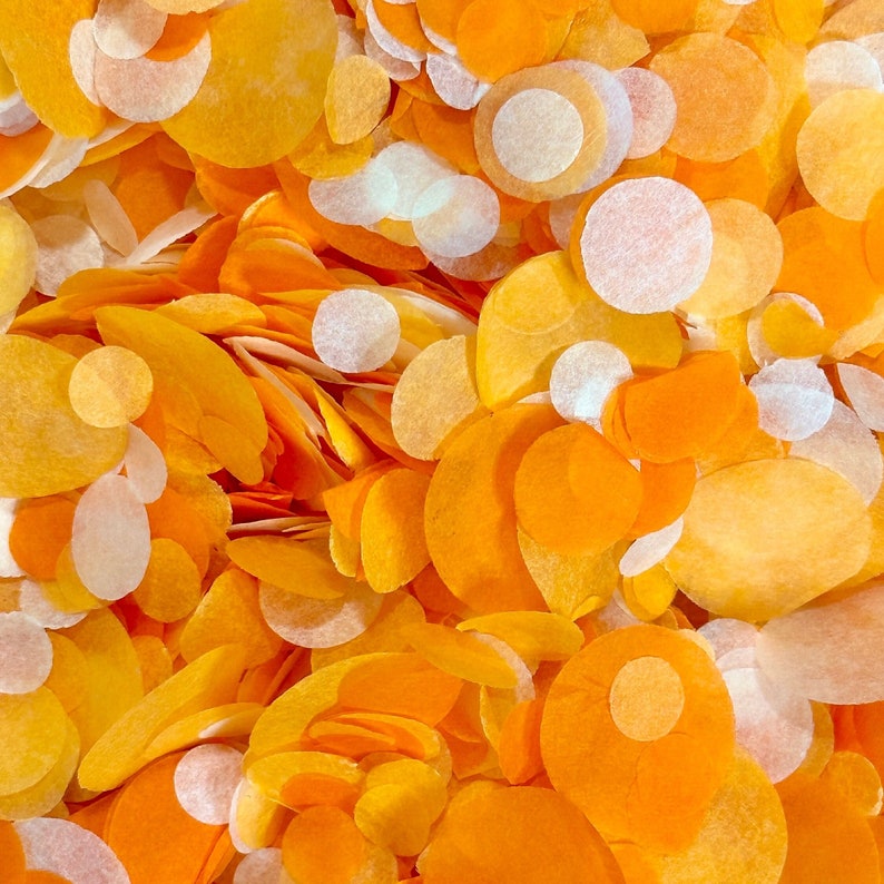 May include: A close-up of a pile of orange and white confetti. The confetti is made of paper and is in various shapes and sizes.