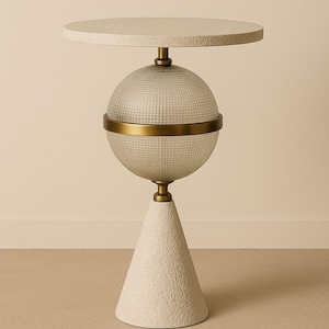 May include: A contemporary side table with a round, textured, off-white top. The table has a clear, textured glass globe with a brass band, supported by a textured, off-white cone-shaped base. The table is approximately 61 cm tall.