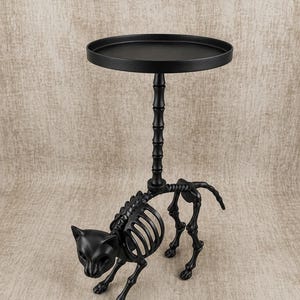 May include: A black metal side table with a cat skeleton design. The table has a round top and a decorative stem. The cat skeleton is in a walking pose, adding a unique touch to the Halloween-themed decor.