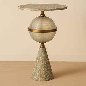 Może przedstawiać: Dekoracyjny stolik boczny z okrągłym blatem i wzorzystą podstawą. Stół posiada przezroczystą, sferyczną szklaną część środkową z mosiężną opaską. Blat i podstawa mają niebiesko-złoty wzór.
