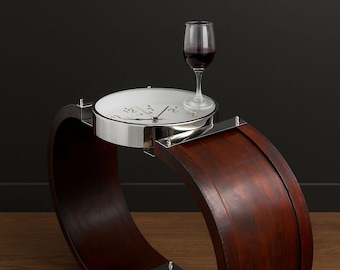 Puede incluir: Una mesa auxiliar única en forma de reloj, con acabado en madera oscura. Cuenta con una esfera circular con detalles plateados y una copa de vino tinto. El diseño es moderno y artístico, adecuado para un salón.