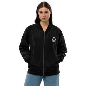 May include: A black bomber jacket with a zipper closure and a silver recycle symbol with the word "RECYC" embroidered on the front.