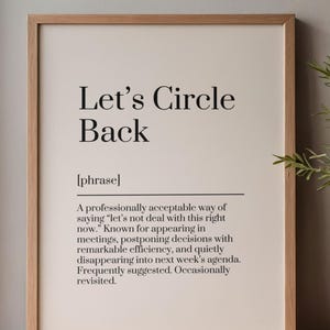May include: A framed wall art print featuring the text Let's Circle Back, defined as a professionally acceptable way of saying let's not deal with this right now. The print is housed in a light-toned wooden frame with a clean, off-white background.