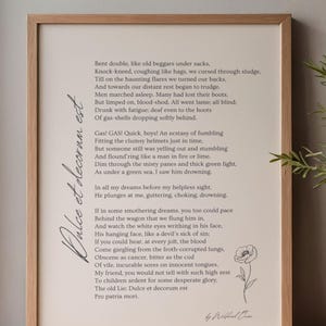 May include: A framed print featuring the poem Dulce et decorum est by Wilfred Owen in black text on a cream background. The design includes a vertical script title, the full poem, a small line drawing of a poppy, and the author's signature.