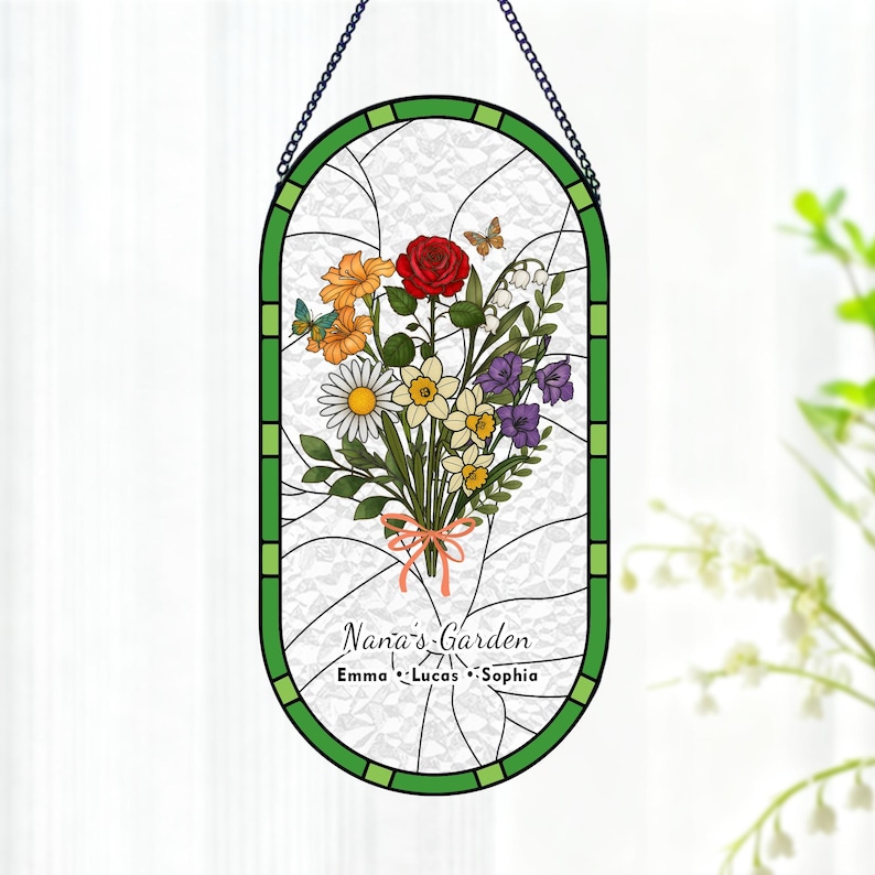 May include: Stained glass window art featuring a bouquet of flowers with a red rose, daisies, and other colorful blooms. The green border surrounds the floral arrangement. Text reads "Nana's Garden" with names below. A decorative piece for the home.