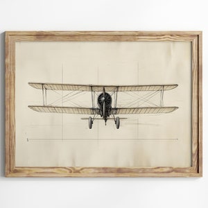 Op de afbeelding: Een ingelijste zwart-witte tekening van een vintage dubbeldekker op een beige achtergrond. Het vliegtuig is met uitgespreide vleugels naar de kijker gericht.