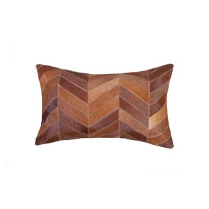 Puede incluir: Cojín rectangular decorativo con un patrón de espiga. El cojín presenta un diseño de patchwork con diferentes tonos de cuero marrón, creando una superficie texturizada y visualmente atractiva. Ideal para la decoración del hogar.