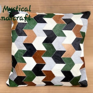 May include: Geometric patterned pillow cover made from cowhide in shades of brown, green, black, and white.