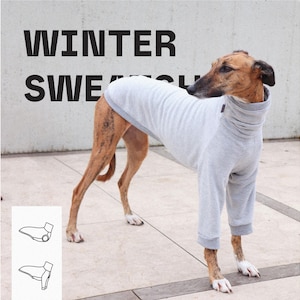 Può includere: Un maglione per cani grigio chiaro con collo alto e maniche lunghe indossato da un cane tigrato. Il testo WINTER SWEATER è visibile sullo sfondo. Un piccolo grafico bianco che mostra il design del capo si trova nell'angolo in basso a sinistra.