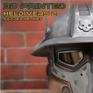 Może przedstawiać: Wydrukowany w 3D hełm Sapper z gry Helldivers 2 o wykończeniu w kolorze zwietrzałego metalicznego szarości. Hełm posiada wyraźny emblemat czaszki na czole, szerokie rondo oraz ciemny wizjer. Tekst na obrazie brzmi: 3D PRINTED HELIDIVERS 2 SAPPER HELMET.
