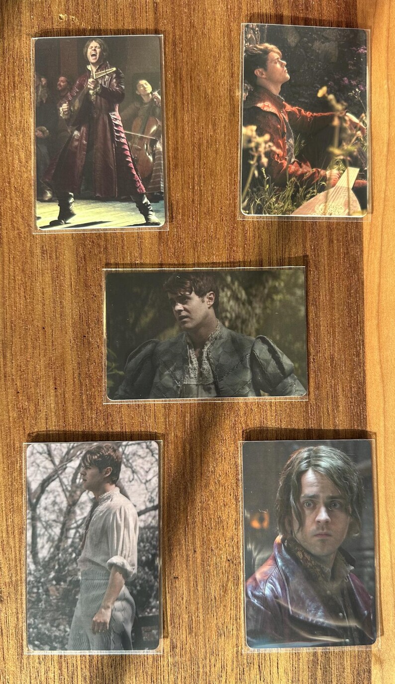 Puede incluir: Conjunto de cinco cromos con im&aacute;genes de un hombre con varios trajes. Las tarjetas muestran al hombre en diferentes escenarios, incluyendo una actuaci&oacute;n, al aire libre y primeros planos. Las tarjetas se muestran sobre una superficie de madera.