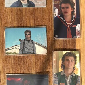 Puede incluir: Conjunto de cinco cromos con im&aacute;genes de una persona con diferentes atuendos. Las tarjetas est&aacute;n protegidas por fundas de pl&aacute;stico transparente. Las im&aacute;genes incluyen una chaqueta, un atuendo de marinero y un chaleco verde.