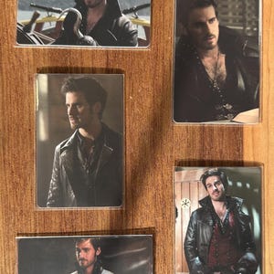 Puede incluir: Conjunto de cinco tarjetas rectangulares con im&aacute;genes de un hombre en varias poses. El hombre lleva una chaqueta de cuero negra y una camisa oscura. Las tarjetas se muestran sobre una superficie de madera.