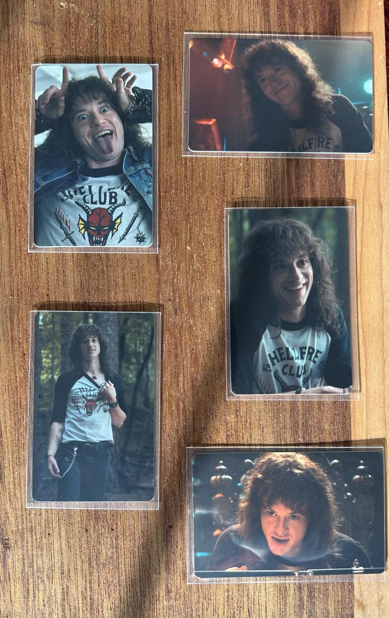 Puede incluir: Una colecci&oacute;n de cinco tarjetas rectangulares con im&aacute;genes de una persona con cabello largo y rizado. Las tarjetas muestran a la persona usando camisas con el texto "HELLFIRE CLUB" y "CLUB". El fondo es una superficie de madera.