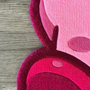 Puede incluir: Una alfombra de felpa rosa y roja con un dise&ntilde;o circular. La alfombra est&aacute; hecha de un material suave y peludo y tiene un patr&oacute;n abstracto &uacute;nico.