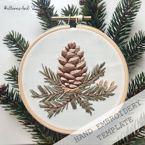 May include: Embroidered pine cone and branches design on a white fabric in a wooden embroidery hoop. The hoop is surrounded by pine branches. The text "HAND EMBROIDERY TEMPLATE" is at the bottom of the image.