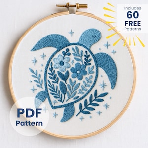 Może przedstawiać: Haftowany wzór żółwia morskiego w odcieniach niebieskiego na białej tkaninie, umieszczony w drewnianej tamborku. Skorupa żółwia ma wzory kwiatowe i liściaste. Tekst zawiera "PDF Pattern" i "Includes 60 FREE Patterns".