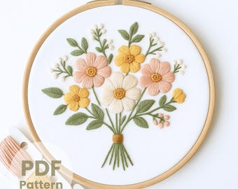 May include: Embroidered floral design in a wooden hoop. The bouquet features peach, yellow, and white flowers with green leaves. The text "PDF Pattern" is visible. Embroidery floss in coordinating colors is in the foreground.
