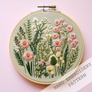 May include: A hand-stitched embroidery hoop with a floral design. The hoop features a variety of flowers in shades of pink, white, and yellow, as well as green leaves. The text "HAND EMBROIDERY PATTERN" is printed on the bottom of the hoop.