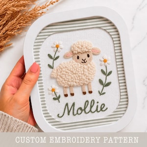 May include: A framed embroidery featuring a fluffy sheep with daisies and the name "Mollie" in green thread. The artwork is set against a striped background within a white frame. The text "CUSTOM EMBROIDERY PATTERN" is at the bottom.
