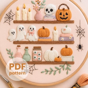 May include: Embroidered Halloween-themed hoop art featuring three shelves with candles, ghosts, pumpkins, a skull, and jars. The text "PDF pattern" is visible. The design includes a spider web and a spider.